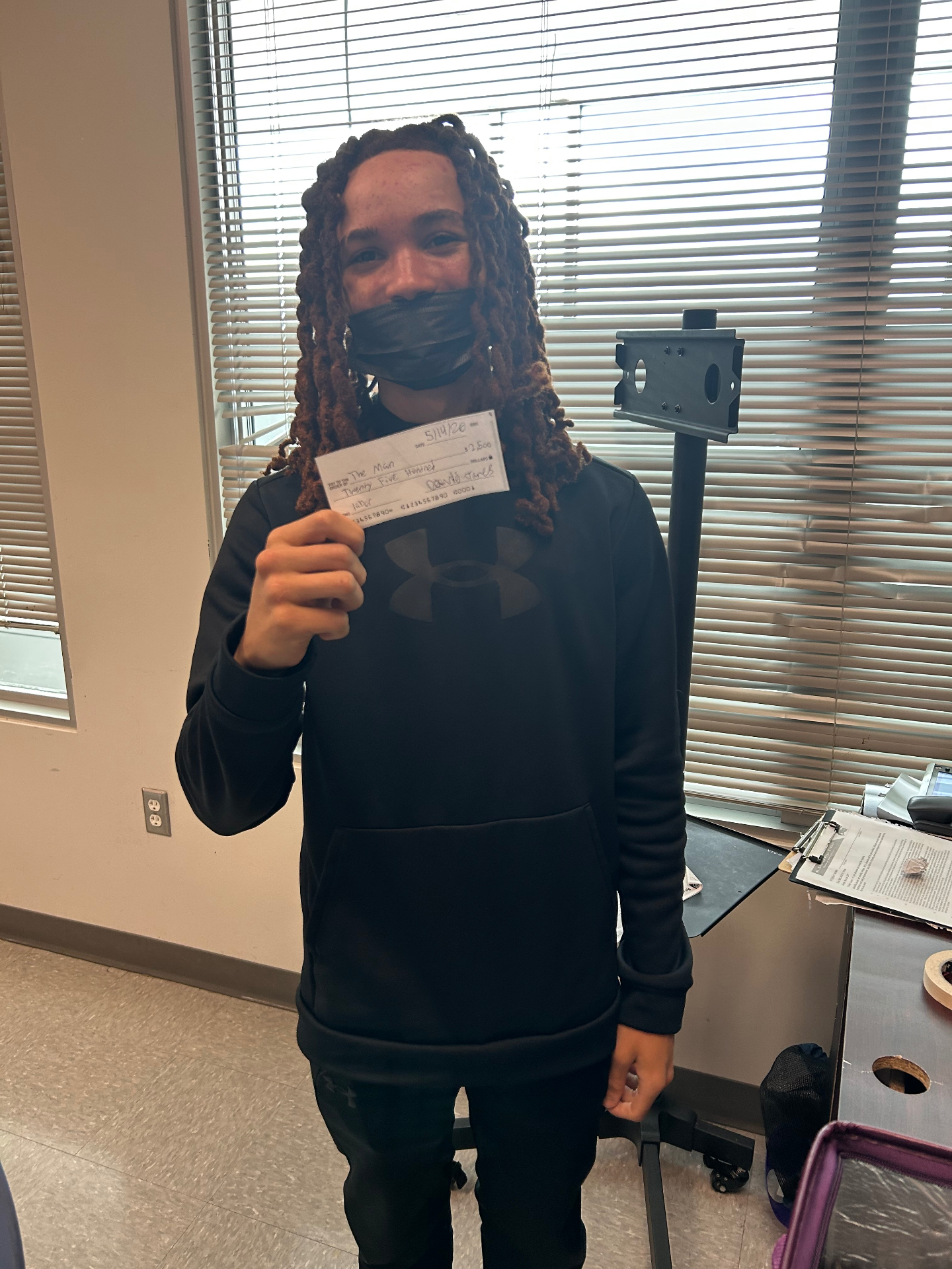 Student holding a check after a Jus One Academy reward moment
